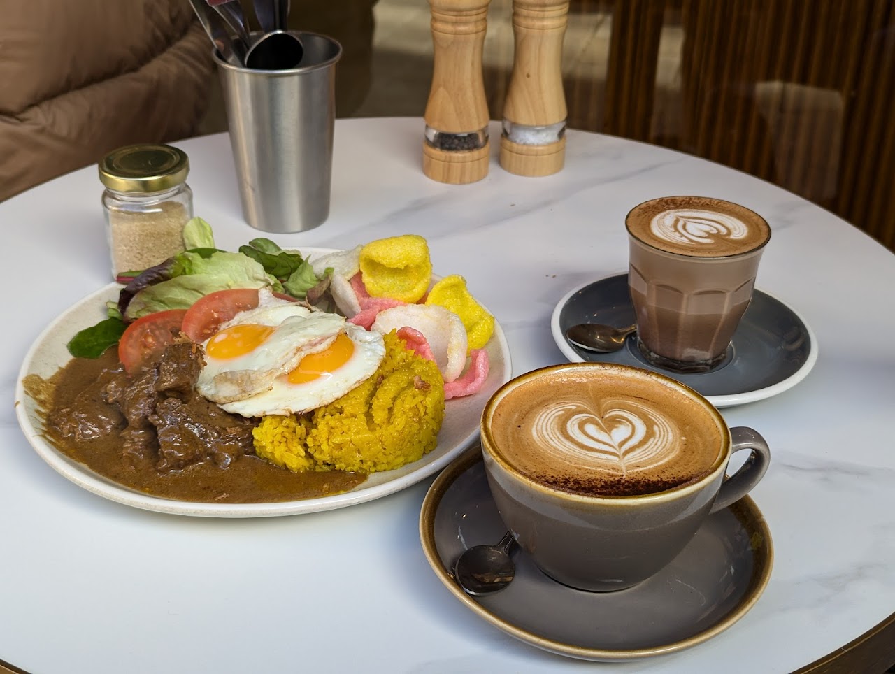 Coffee beside beef rendang style plate with turmeric rice